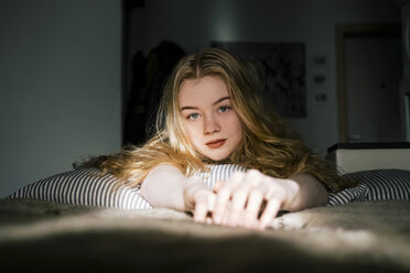 Porträt einer Frau mit blondem Haar, die zu Hause auf dem Bett liegt - CAVF61619