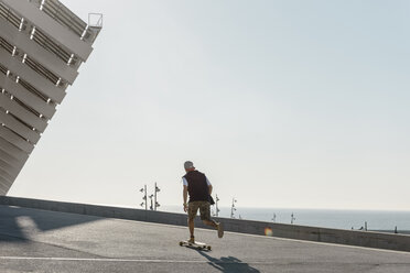 Rückansicht eines Mannes, der auf der Straße Skateboard fährt, gegen einen klaren Himmel an einem sonnigen Tag - CAVF61647