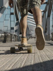 Niedriger Ausschnitt eines Mannes beim Skateboardfahren auf einer Fußgängerbrücke an einem sonnigen Tag - CAVF61662