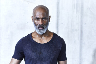 Portrait of sweating bald man with grey beard wearing dark blue jersey - FMKF05420
