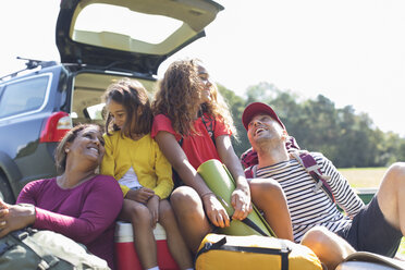 Glückliche Familie mit Campingausrüstung auf dem Rücksitz des Autos - CAIF22794