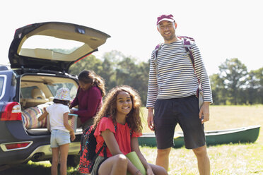 Portrait happy father and daughter camping, unloading car - CAIF22797