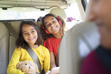 Happy sisters riding in back seat of car - CAIF22804