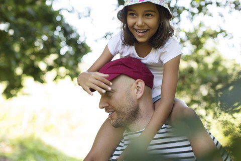 Vater trägt glückliche Tochter auf den Schultern, lizenzfreies Stockfoto