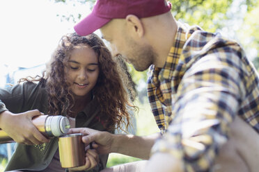 Tochter gießt Kaffee aus einem isolierten Getränkebehälter für ihren Vater ein - CAIF22830