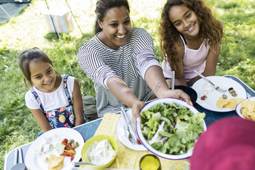 Glückliche Mutter und Töchter genießen Salat zum Mittagessen am Campingtisch - CAIF22836