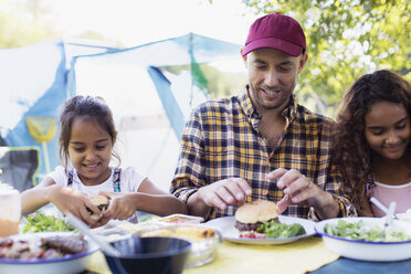 Vater und Töchter genießen ein Hamburger-Mittagessen auf dem Campingplatz - CAIF22852