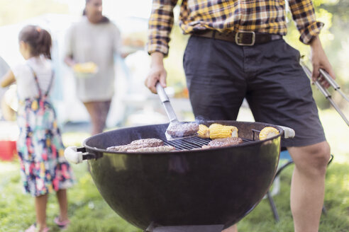 Mann beim Grillen von Hamburgern auf dem Campingplatz - CAIF22855