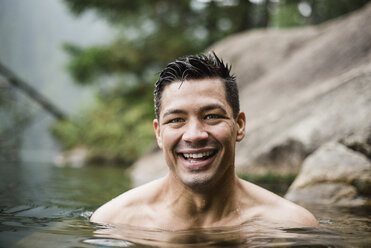 Porträt lächelnder, gut aussehender junger Mann beim Schwimmen im See - CAIF22875