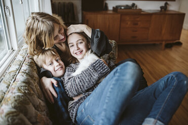 Portrait affectionate mother and children with guinea pig on living room sofa - CAIF22881