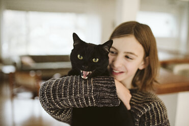 Portrait girl holding hissing black cat - CAIF22882