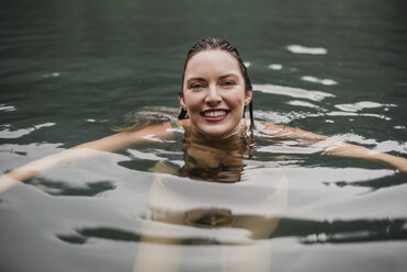 Portrait smiling young woman swimming in lake - CAIF22886