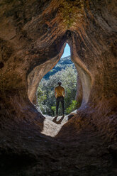 Young man standing in cave entrance, Cova Simanya,Barcelona, Spain - AFVF02477