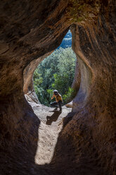 Junger Mann beim Fotografieren am Höhleneingang, Cova Simanya, Barcelona, Spanien - AFVF02478