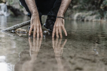 Junger Mann berührt das Wasser in der Nähe der Cova Simanya, Barcelona, Spanien. - AFVF02485