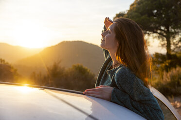 Young woman on a road trip, taking a break, shielding eyes - AFVF02489