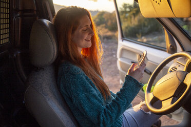 Junge Frau auf einer Autoreise, mit Smartphone - AFVF02494