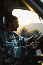 Young man on a road trip, using smartphone - AFVF02497