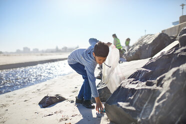 Freiwilliger Junge sammelt Müll am sonnigen Strand auf - CAIF22899