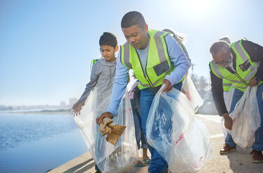 Mehrgenerationen-Familienmänner arbeiten ehrenamtlich und sammeln Müll am Pier auf - CAIF22901