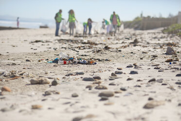 Freiwillige beseitigen Müll am sonnigen Sandstrand - CAIF22904