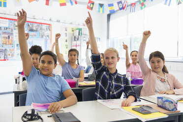 Eifrige Schüler der Junior High School mit erhobenen Händen im Klassenzimmer - CAIF22912