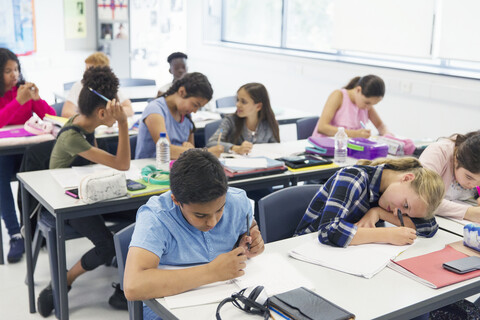 Schüler der Junior High School lernen an Tischen im Klassenzimmer, lizenzfreies Stockfoto