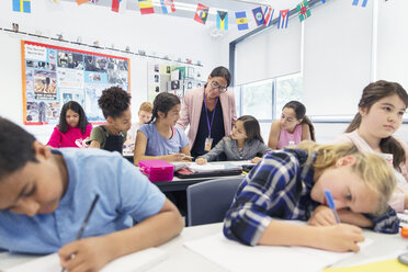 Eine Lehrerin hilft einer Schülerin der Junior High School bei den Hausaufgaben am Schreibtisch im Klassenzimmer - CAIF22917