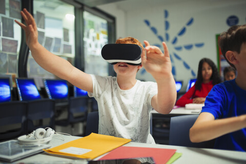 Neugieriger Schüler der Junior High School benutzt einen Virtual-Reality-Simulator im Klassenzimmer, lizenzfreies Stockfoto