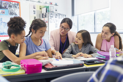 Weibliche Lehrerin und Schülerin der Junior High School lernen am Schreibtisch im Klassenzimmer, lizenzfreies Stockfoto