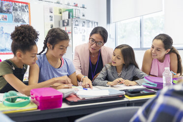 Female teacher and junior high school girl students studying at desk in classroom - CAIF22927