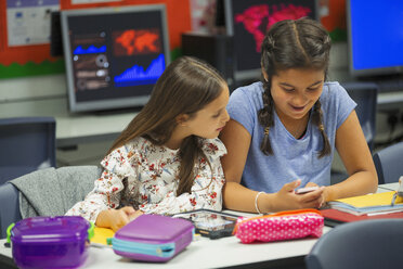 Schülerin der Junior High School benutzt ihr Smartphone am Schreibtisch im Klassenzimmer - CAIF22932