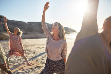 Gelassene Frau übt die umgekehrte Kriegerpose am sonnigen Strand während eines Yoga-Retreats - CAIF22952