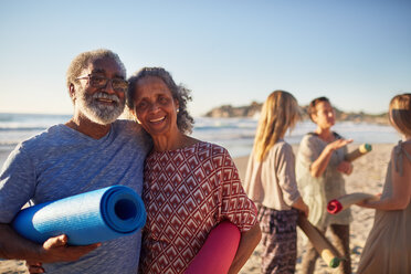 Portrait glückliches älteres Paar mit Yogamatten am sonnigen Strand während eines Yoga-Retreats - CAIF22955