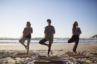 Mother with daughter and friend doing a yoga exercise on the beach stock  photo