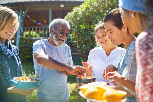 Friends enjoying healthy food outside sunny hut during yoga retreat - CAIF22984