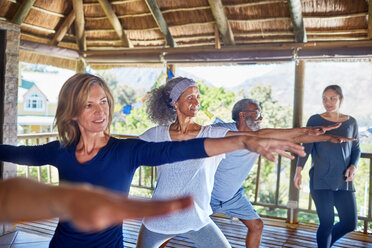 Yoga class practicing warrior 2 pose in hut during yoga retreat - CAIF22990