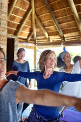 Selbstbewusste Frau, die während eines Yoga-Retreats in einer Hütte die 2-Krieger-Pose übt - CAIF22993