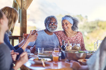 Ein glückliches älteres Paar genießt eine gesunde Mahlzeit in einer Hütte während eines Yoga-Retreats - CAIF22994