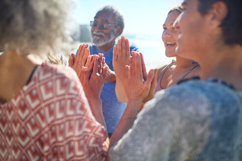 Freunde mit verschränkten Händen im Kreis bei einem Yoga-Retreat - CAIF23004