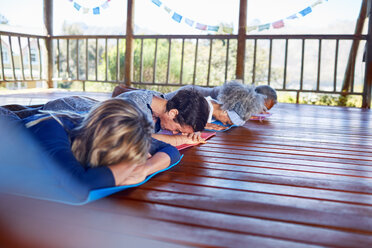 Gelassene Menschen meditieren in einer Hütte während eines Yoga-Retreats - CAIF23012