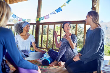 Women talking in hut during yoga retreat - CAIF23018
