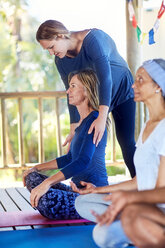 Lehrerin passt die Schultern eines Schülers während eines Yoga-Kurses an - CAIF23026