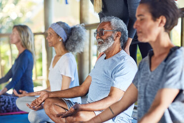 Gelassener älterer Mann meditiert während eines Yoga-Retreats - CAIF23028