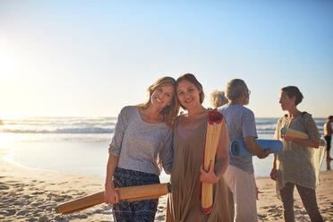 Portrait glückliche Mutter und Tochter mit Yogamatten am sonnigen Strand während eines Yoga-Retreats - CAIF23039