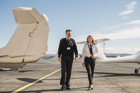 Piloten im Gespräch auf der Start- und Landebahn eines Flughafens vor blauem Himmel an einem sonnigen Tag - CAVF61808