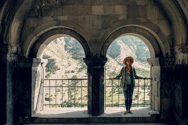 Woman wearing hat while standing at observation point against mountain - CAVF61888