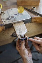 Abgeschnittene Hände einer Juwelierin, die einen Ring mit einer Raspel in einer Werkstatt feilt - CAVF61948
