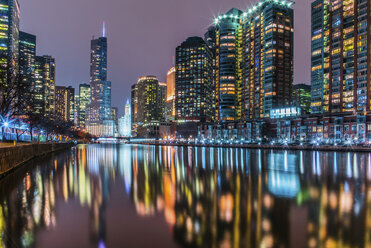 Beleuchtete moderne Gebäude, die sich auf dem ruhigen Chicago River vor dem nächtlichen Himmel spiegeln - CAVF61987