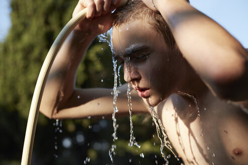 Jugendlicher erfrischt sich mit Wasser aus dem Gartenschlauch - AMEF00001